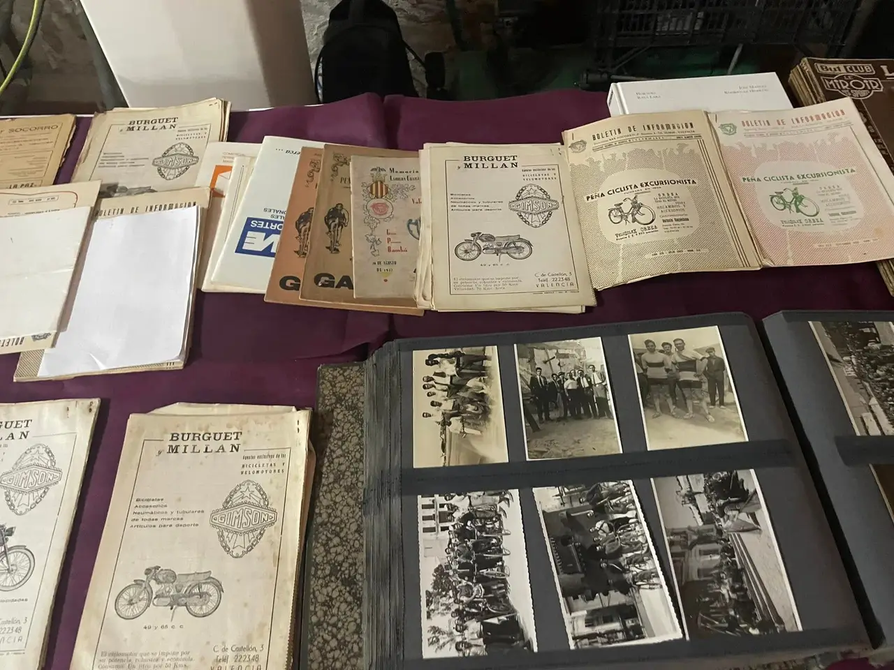 Boletines de información de la Peña de los años sesenta extendidos sobre una mesa, junto a un álbum abierto de fotografías antiguas